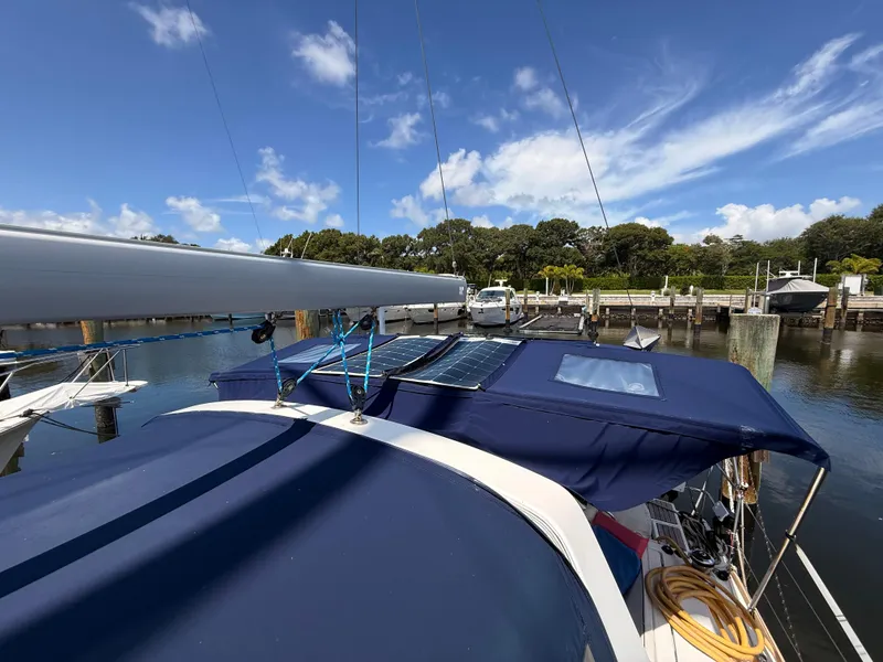 Slide: The Image of 2016 Beneteau Oceanis 45 sailboat docked, featuring solar panels and blue canopy under clear sky. - 24