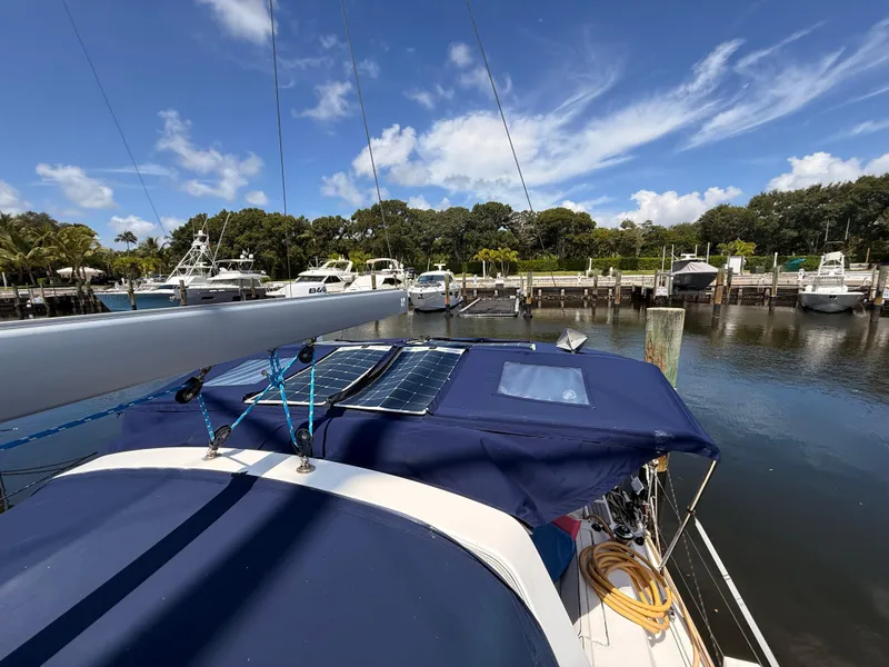 Slide: The Image of 2016 Beneteau Oceanis 45 sailboat docked, featuring solar panels and blue canopy under a clear sky. - 25