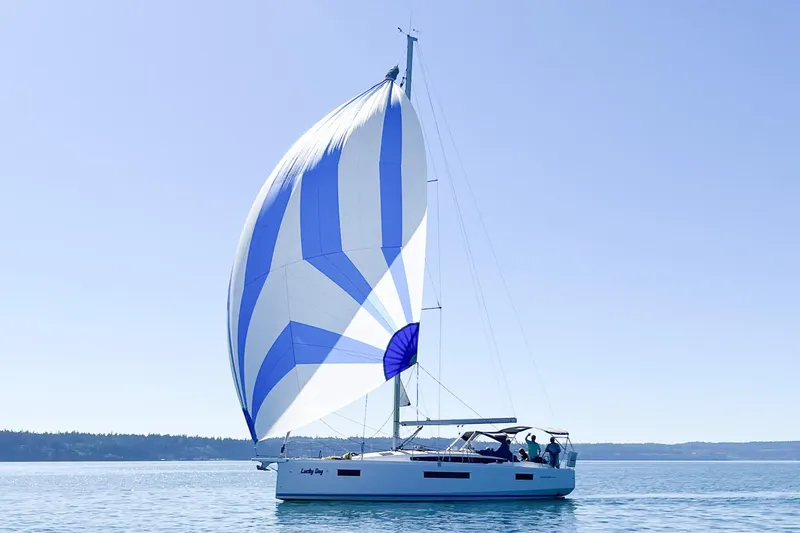 Slide: The Image of 2023 Jeanneau Sun Odyssey 410 sailing with blue and white spinnaker on calm waters. - 20