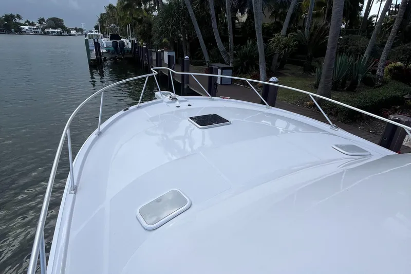 Slide: The Image of 2000 Luhrs Tournament 360 Convertible boat docked by lush greenery. - 14