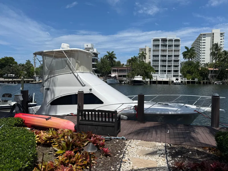 Slide: The Image of 2000 Luhrs Tournament 360 Convertible yacht docked by waterfront, surrounded by lush greenery and buildings. - 2