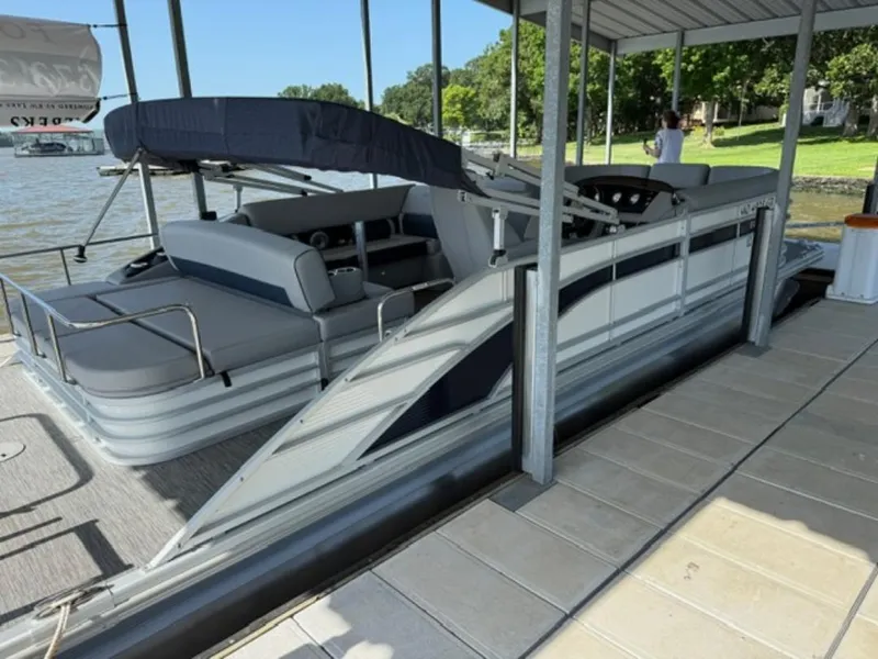 Slide: The Image of 2022 Bennington 23 LSB pontoon boat docked under a covered area by the lake. - 4