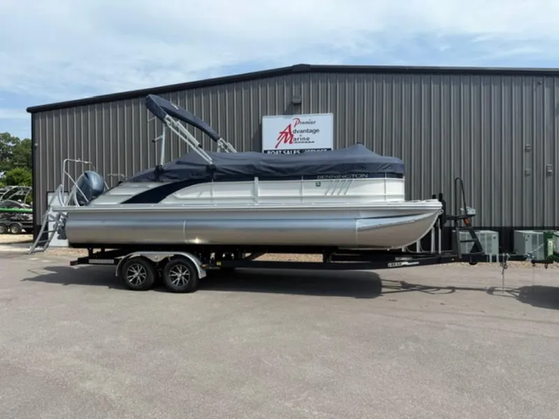 The Image of 2022 Bennington 23 LSB pontoon boat on trailer outside a metal building. - 1