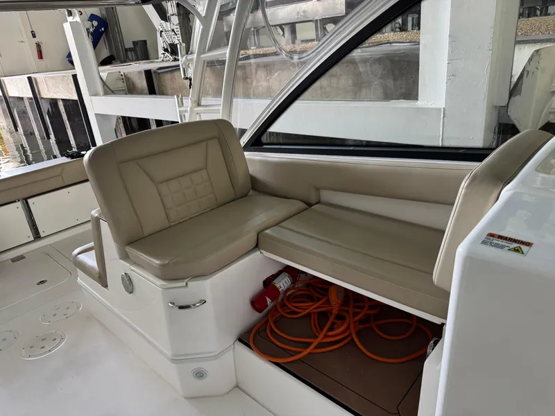 Slide: The Image of 2019 Everglades 340 Dual Console boat interior with beige seating and storage compartment. - 12