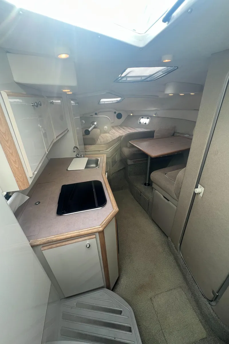 Slide: The Image of 1997 Maxum 2800 SCR cabin interior with kitchenette, seating, and skylight. - 10