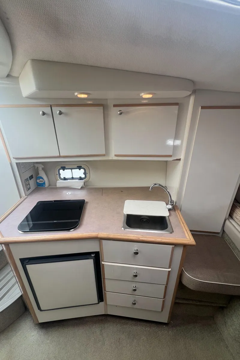 Slide: The Image of 1997 Maxum 2800 SCR boat interior kitchen with sink, stove, and storage cabinets. - 13