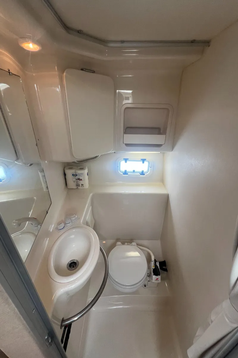 Slide: The Image of 1997 Maxum 2800 SCR boat bathroom with sink, toilet, and small window. - 14