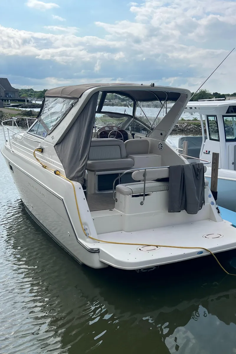 Slide: The Image of 1997 Maxum 2800 SCR boat docked in calm waters, featuring a covered seating area. - 5