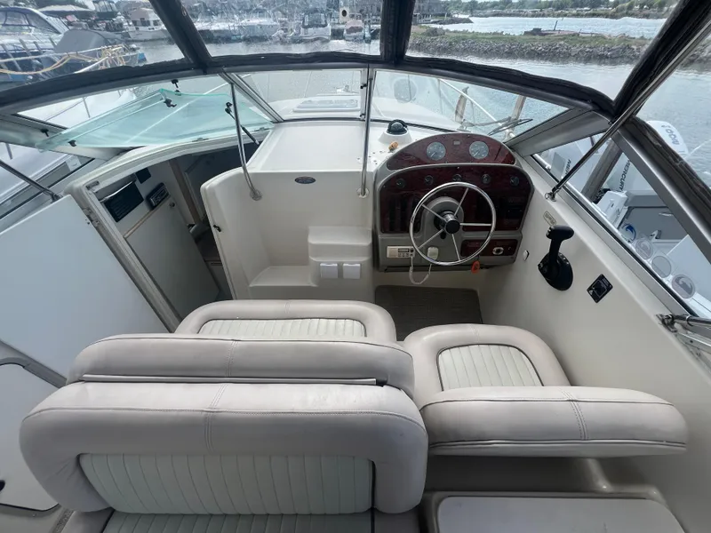 Slide: The Image of 1997 Maxum 2800 SCR boat cockpit with steering wheel and seating, overlooking marina. - 8