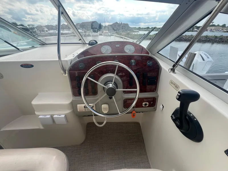 Slide: The Image of 1997 Maxum 2800 SCR boat helm with steering wheel and control panel, docked by the water. - 9