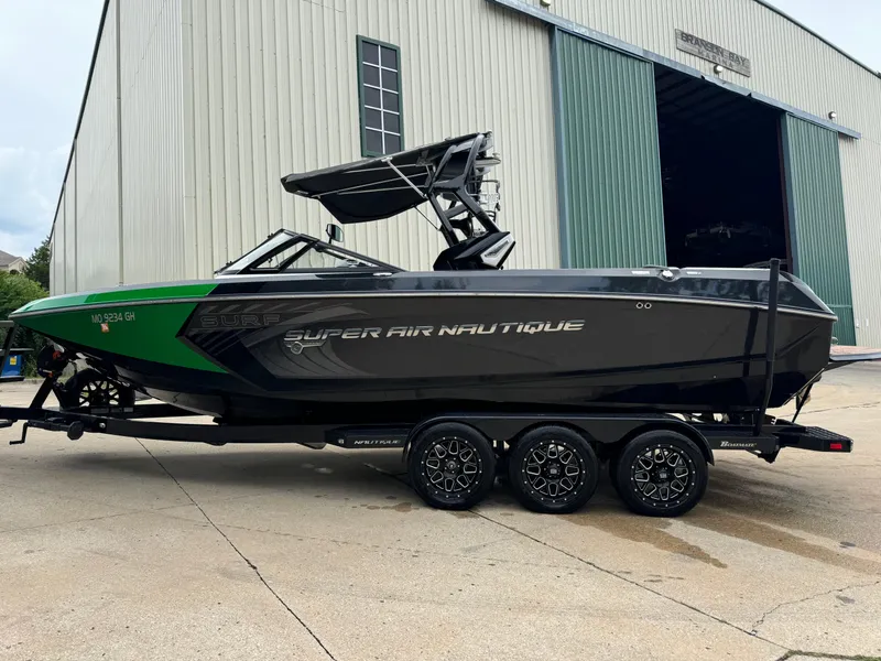 Slide: The Image of 2017 Nautique Super Air Nautique G25 boat on trailer near large warehouse. - 3