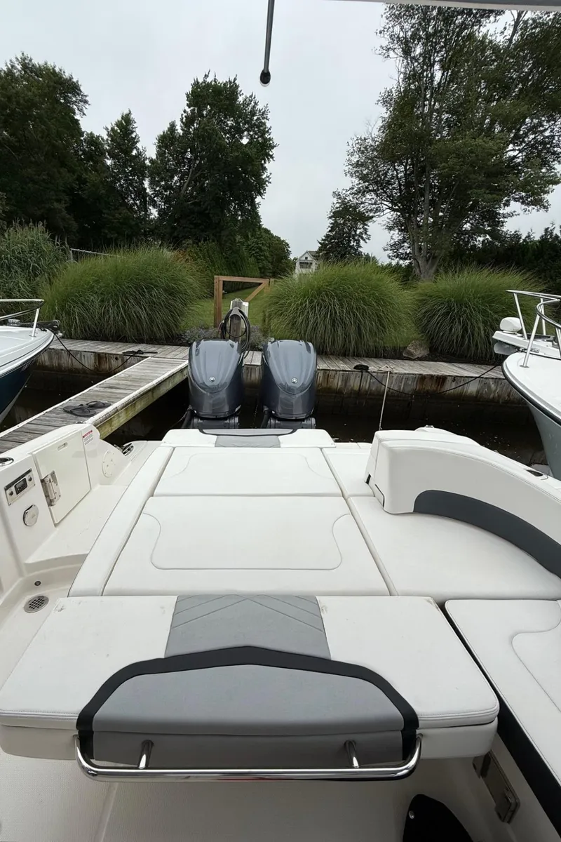 Slide: The Image of 2021 Chaparral 300 OSX boat docked, featuring dual outboard motors and lush greenery backdrop. - 10