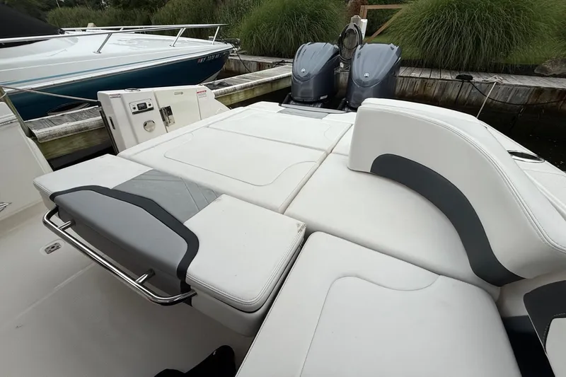 Slide: The Image of 2021 Chaparral 300 OSX boat interior with cushioned seating and dual outboard motors. - 11