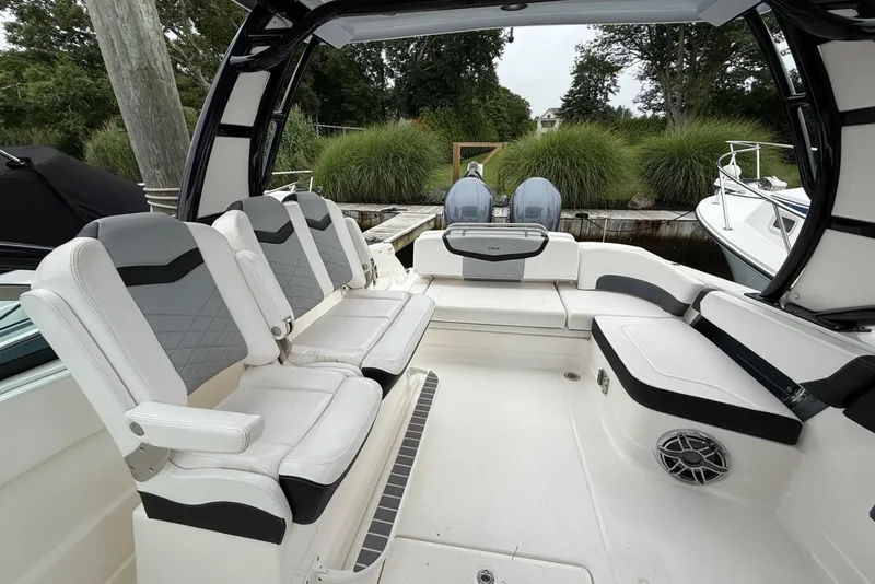 Slide: The Image of 2021 Chaparral 300 OSX boat interior with cushioned seating and dual outboard motors. - 14