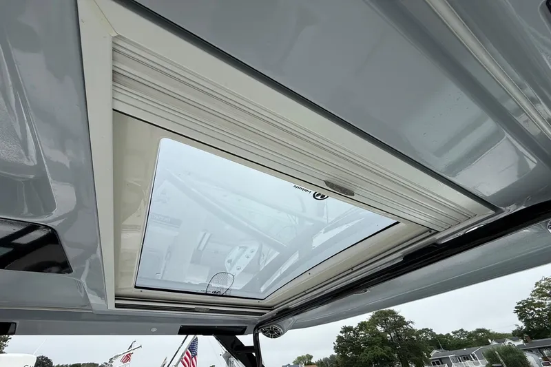 Slide: The Image of 2021 Chaparral 300 OSX boat sunroof view with clear sky and trees. - 15