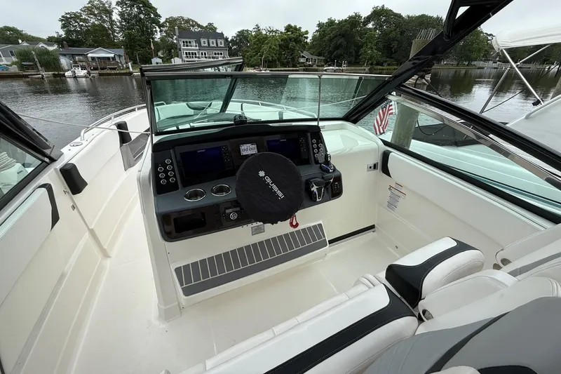 Slide: The Image of 2021 Chaparral 300 OSX boat cockpit with modern controls and waterfront view. - 16