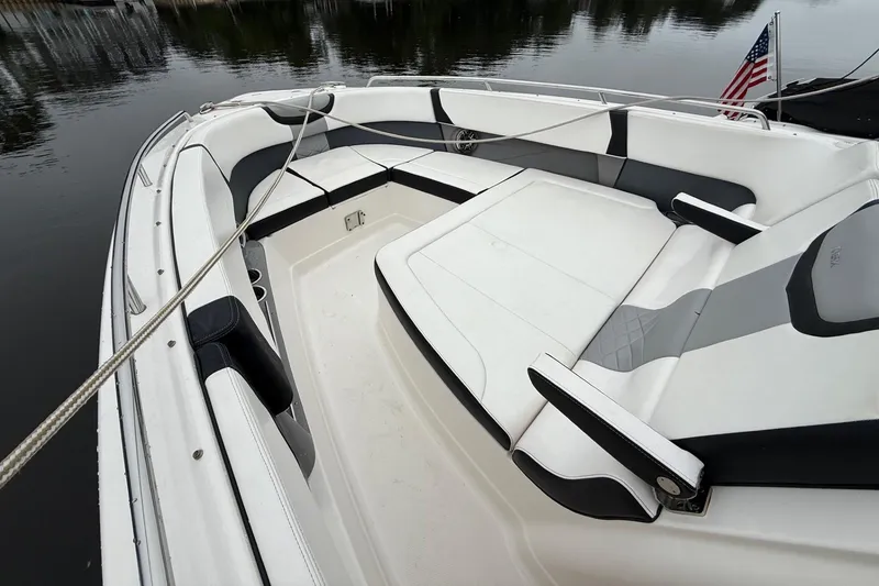 Slide: The Image of 2021 Chaparral 300 OSX boat interior with white and gray seating, docked by calm water. - 17