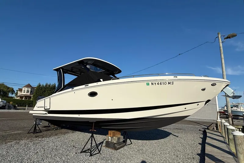 Slide: The Image of 2021 Chaparral 300 OSX boat on display, parked on gravel under a clear blue sky. - 2