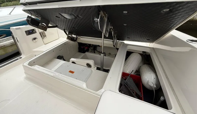 Slide: The Image of 2021 Chaparral 300 OSX boat storage compartments open, revealing equipment and accessories. - 28