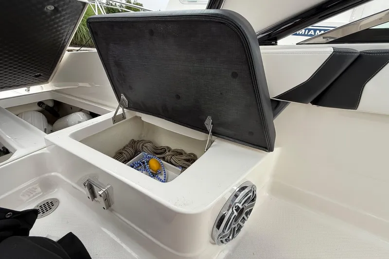 Slide: The Image of Open storage compartment on 2021 Chaparral 300 OSX boat, containing ropes and a yellow buoy. - 29