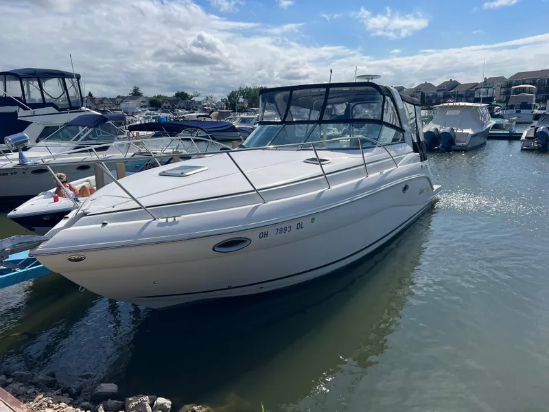 The Image of 2003 Rinker 312 Fiesta Vee boat docked in a marina under a partly cloudy sky. - 0
