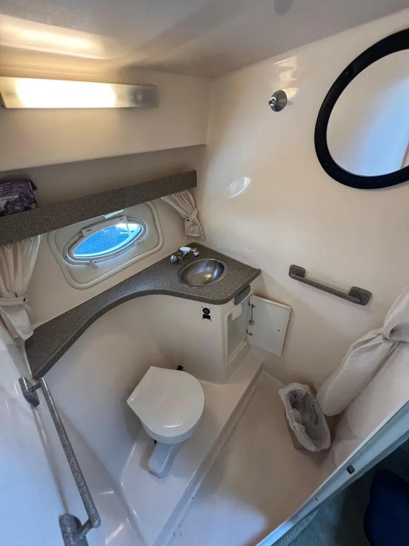 Slide: The Image of 2003 Rinker 312 Fiesta Vee boat bathroom with sink, toilet, and porthole window. - 15