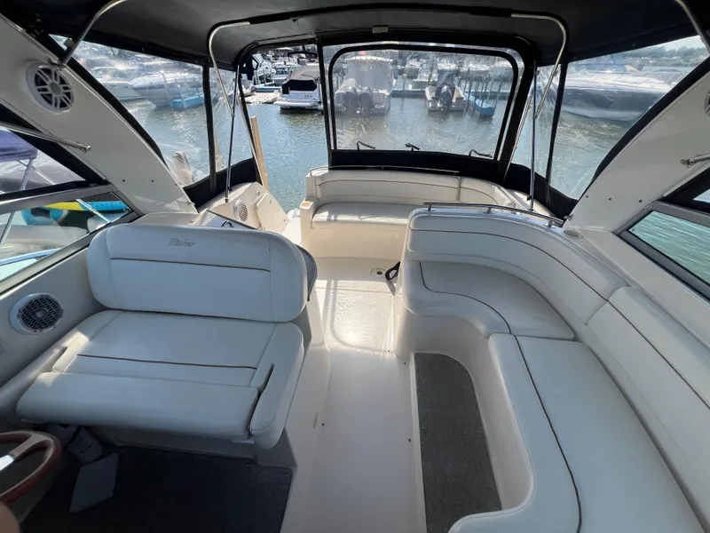 Slide: The Image of Interior of 2003 Rinker 312 Fiesta Vee boat with white seating and marina view. - 9