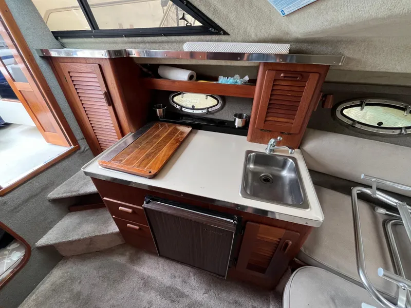 Slide: The Image of 1986 Tiara Yachts Continental interior kitchen with sink, wooden cabinets, and cutting board. - 17