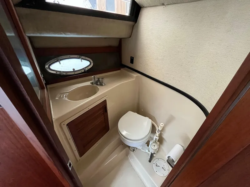 Slide: The Image of 1986 Tiara Yachts Continental bathroom with sink, toilet, and porthole window. - 19