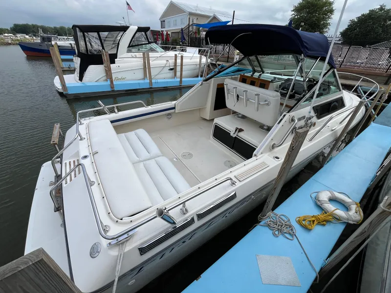 Slide: The Image of 1986 Tiara Yachts Continental docked at marina, featuring spacious seating and canopy. - 4