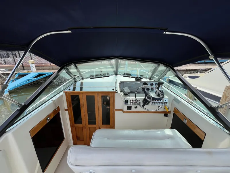 Slide: The Image of 1986 Tiara Yachts Continental cockpit with steering wheel, dashboard, and wooden accents. - 6