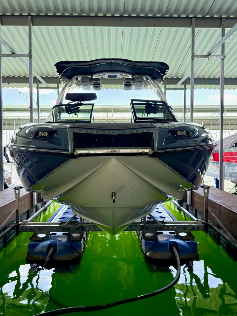 Slide: The Image of 2017 Centurion Ri237 boat in dock, viewed from front, under covered structure. - 17