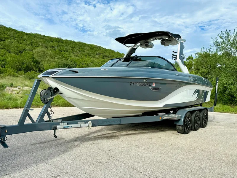 Slide: The Image of 2017 Centurion Ri237 boat on trailer, parked outdoors with green hills in background. - 24