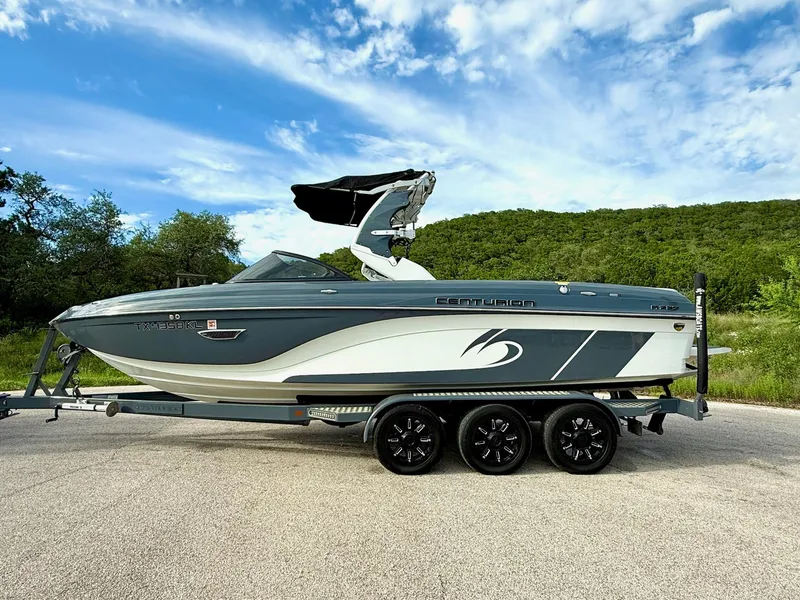 Slide: The Image of 2017 Centurion Ri237 boat on trailer, parked on road with lush green background. - 25