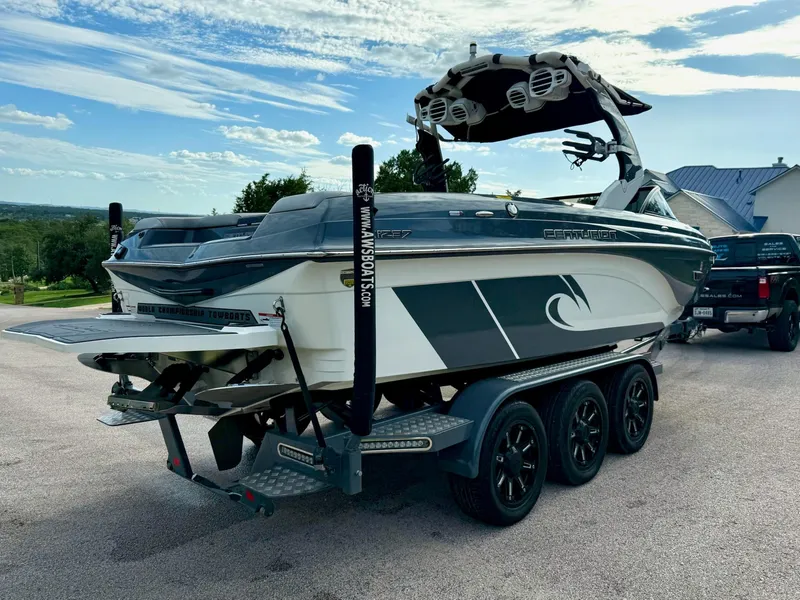 Slide: The Image of 2017 Centurion Ri237 boat on trailer, parked outdoors under a partly cloudy sky. - 28