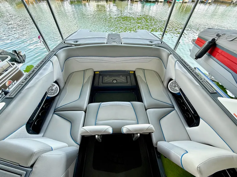 Slide: The Image of 2017 Centurion Ri237 boat interior with gray seating and cup holders, docked by the water. - 38