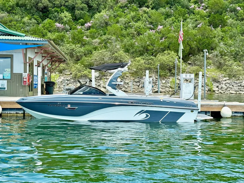 Slide: The Image of 2017 Centurion Ri237 boat docked on a serene lake with lush greenery. - 9