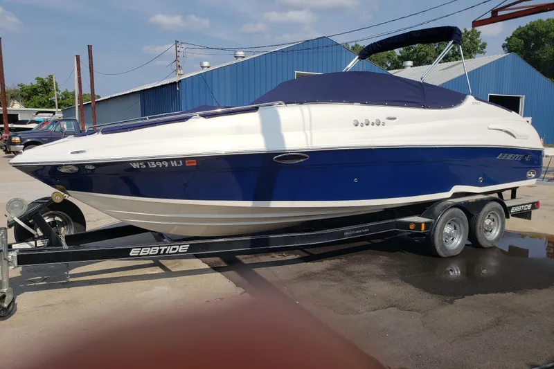The Image of 2006 Ebbtide 2300 BRL boat on trailer, blue and white design, parked outdoors. - 0