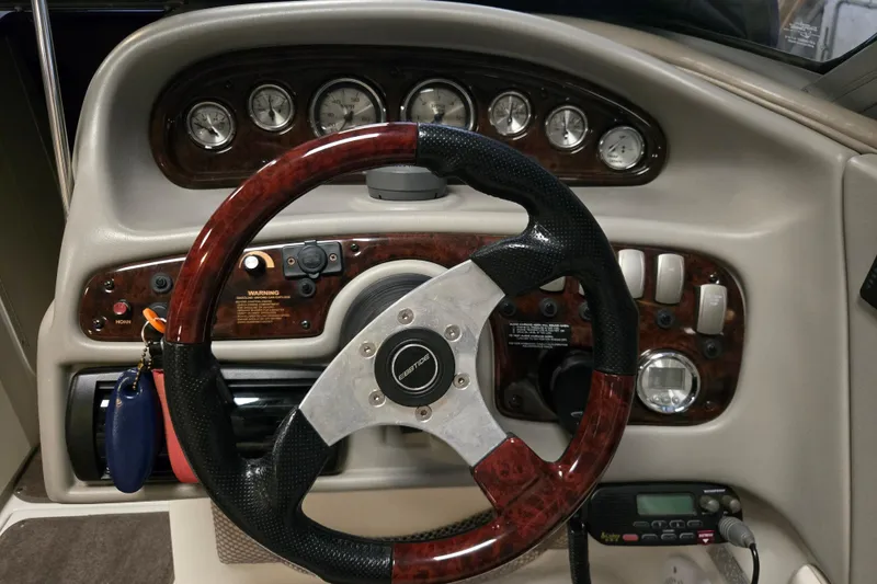 Slide: The Image of 2006 Ebbtide 2300 BRL boat dashboard with wood-trimmed steering wheel and control panel. - 12