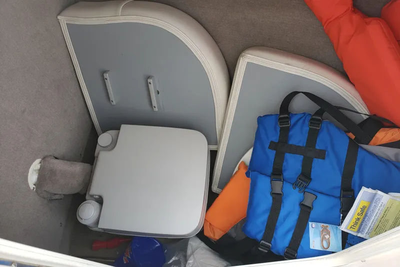Slide: The Image of Storage compartment in a 2006 Ebbtide 2300 BRL boat with life jacket and pump-out portable toilet. - 17