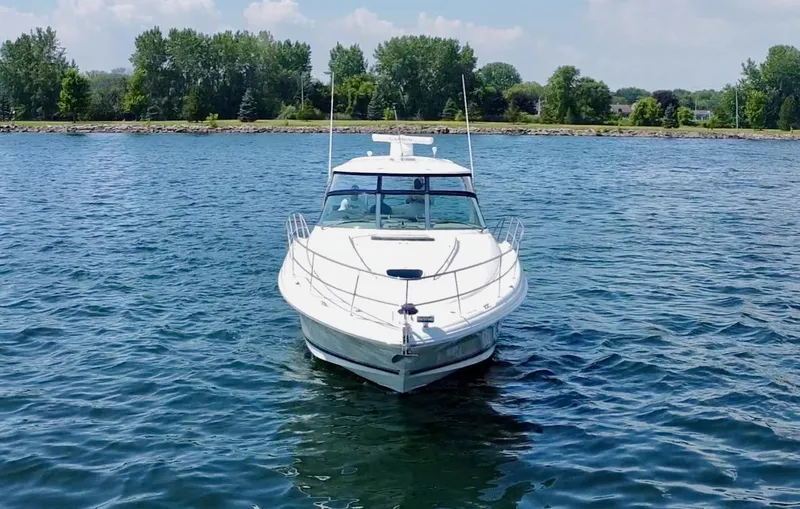 Slide: The Image of 2006 Sea Ray 44 Sundancer yacht on a serene lake with lush green shoreline. - 12