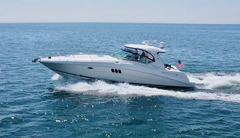 Slide: The Image of 2006 Sea Ray 44 Sundancer cruising on open water, displaying sleek design and American flag. - 4