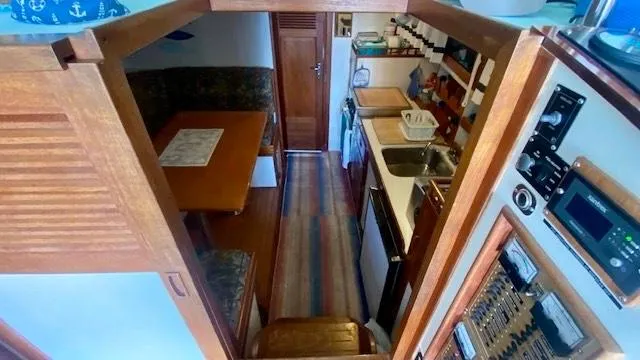Slide: The Image of Interior of 1987 Roughwater 37 boat with kitchen and dining area, featuring wood finishes. - 10