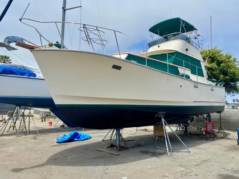 Slide: The Image of 1987 Roughwater 37 boat on dry dock, with green canopy and white hull. - 2