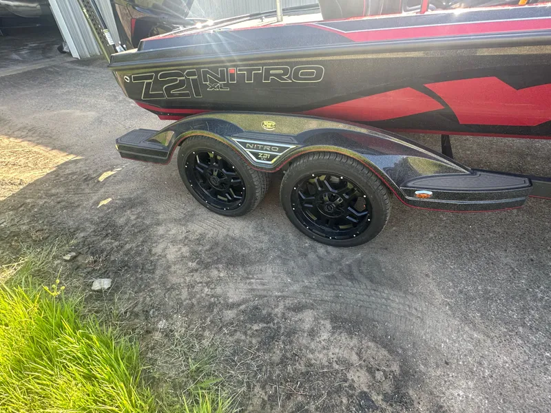Slide: The Image of 2024 Nitro Z21XL boat trailer with black wheels on a driveway. - 6