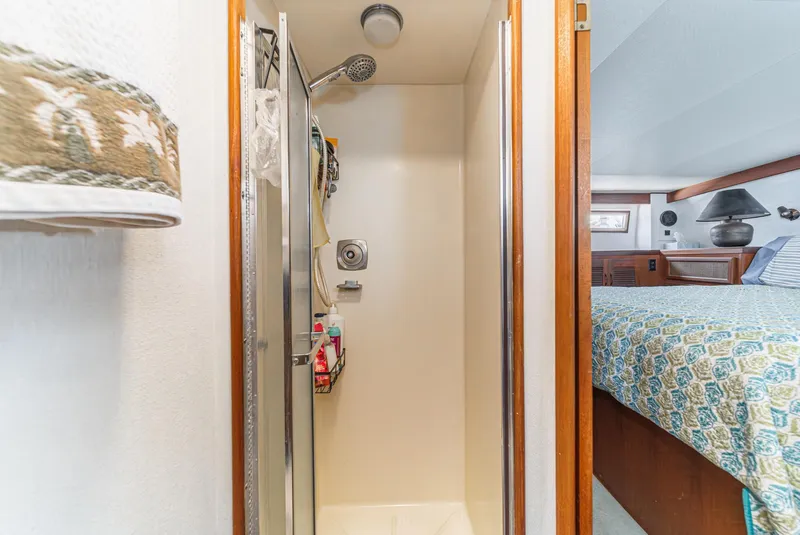 Slide: The Image of 1982 Viking 44 Motor Yacht shower and bedroom interior with patterned bedding. - 10