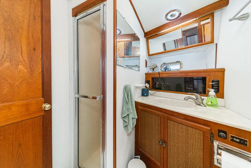 Slide: The Image of 1982 Viking 44 Motor Yacht bathroom with shower, wooden cabinetry, and sink area. - 15
