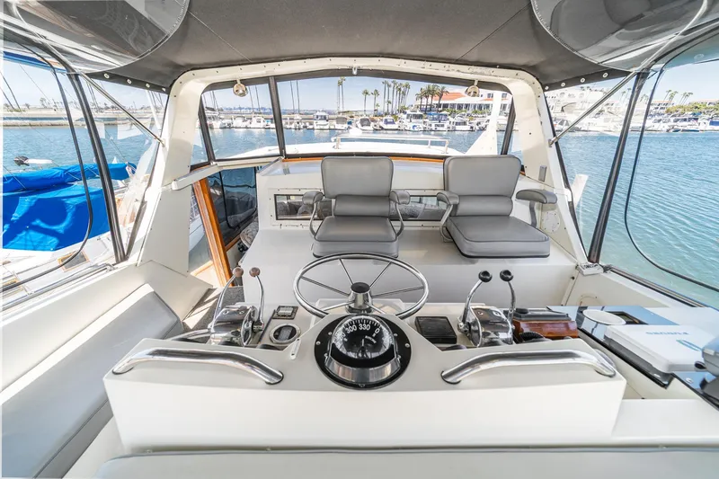 Slide: The Image of 1982 Viking 44 Motor Yacht helm with dual seats, steering wheel, and marina view. - 33