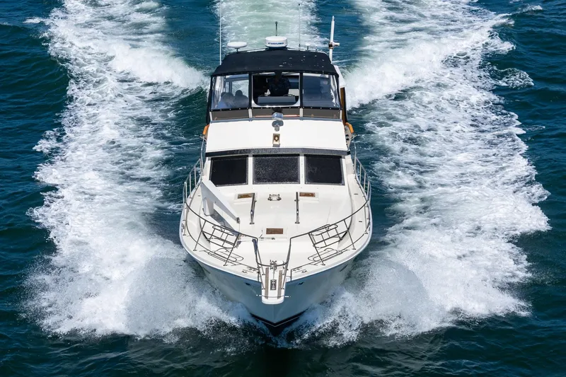 Slide: The Image of 1982 Viking 44 Motor Yacht cruising on open water, creating a dynamic wake. - 38