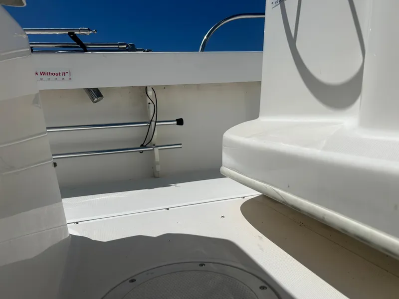Slide: The Image of 2004 Boston Whaler 190 Nantucket boat interior with seating and railing under clear blue sky. - 20
